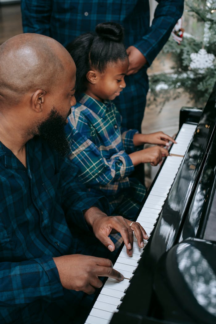 Black father with son and daughter playing piano at home